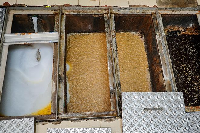 maintenance worker performing grease trap cleaning